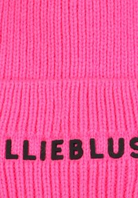Felle roze gebreide stof met zwarte letters die "LIEBLUS" op de ribbelachtige oppervlakte zijn genaaid.