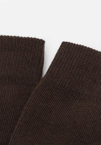 Brune strikkede sokker med et struktureret ribkant. Materialet er blødt, og formen er standard for ankel-lange sokker.
