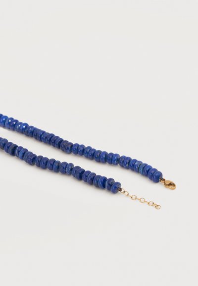 Collier de perles rondes bleu profond poli avec fermoir mousqueton doré et chaîne courte réglable sur fond blanc.