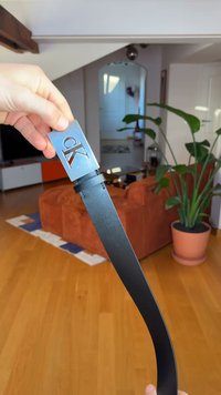 Mustast nahast vöö hõbedase metallist pandlaga, millel on lõigatud "CK"-logo. Sile tekstuur, kergelt kõverdatud disain, hoiab käsi.