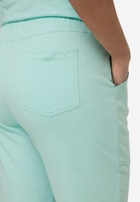 Pantalones jogger de algodón en verde menta con una cintura elástica y un solo bolsillo trasero, que presentan una textura suave y un corte relajado.