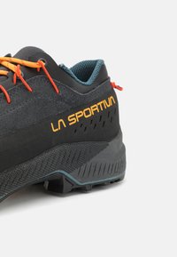 Graue und schwarze Wanderschuhe mit orangefarbenen Schnürsenkeln, strukturiertem Obermaterial und prominenter "LA SPORTIV"-Logo. Verfügt über eine strapazierfähige Gummisohle und ausgeprägte Muster.