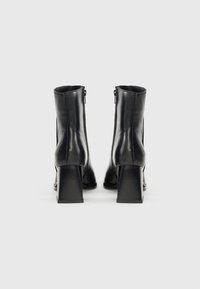 Black leather ankle boots with a smooth texture, square block heels, and a zipper detail at the back.