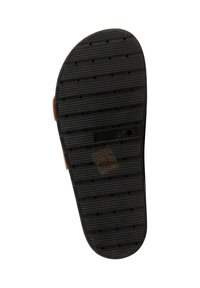 Semelle d'une sandale noire avec des rainures horizontales, de petits trous circulaires et une étiquette marquée "38" sur un fond blanc.