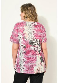 Kortärmad topp i livlig rosa med blommiga och abstrakta mönster, med en lätt böjd nederkant och en avslappnad passform.