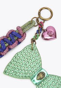 Brelok z plecionym paskiem w kolorze różowym, niebieskim i zielonym kryształem, z metalową zieloną kokardką oraz różowym serduszkiem.