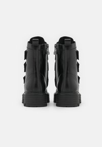 Bottines en cuir noir avec une finition lisse, fermeture éclair et sangles ajustables. Semelle texturée pour une adhérence et une stabilité optimales.