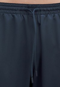 Marina idrottsshorts har en elastisk midja med dragsko, en slät yta och inga ytterligare mönster eller detaljer.