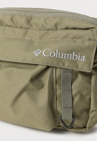 Πράσινο υφασμάτινο πουγκί με υφή, διαθέτει φερμουάρ και λογότυπο Columbia σε ασημί χρώμα μπροστά.