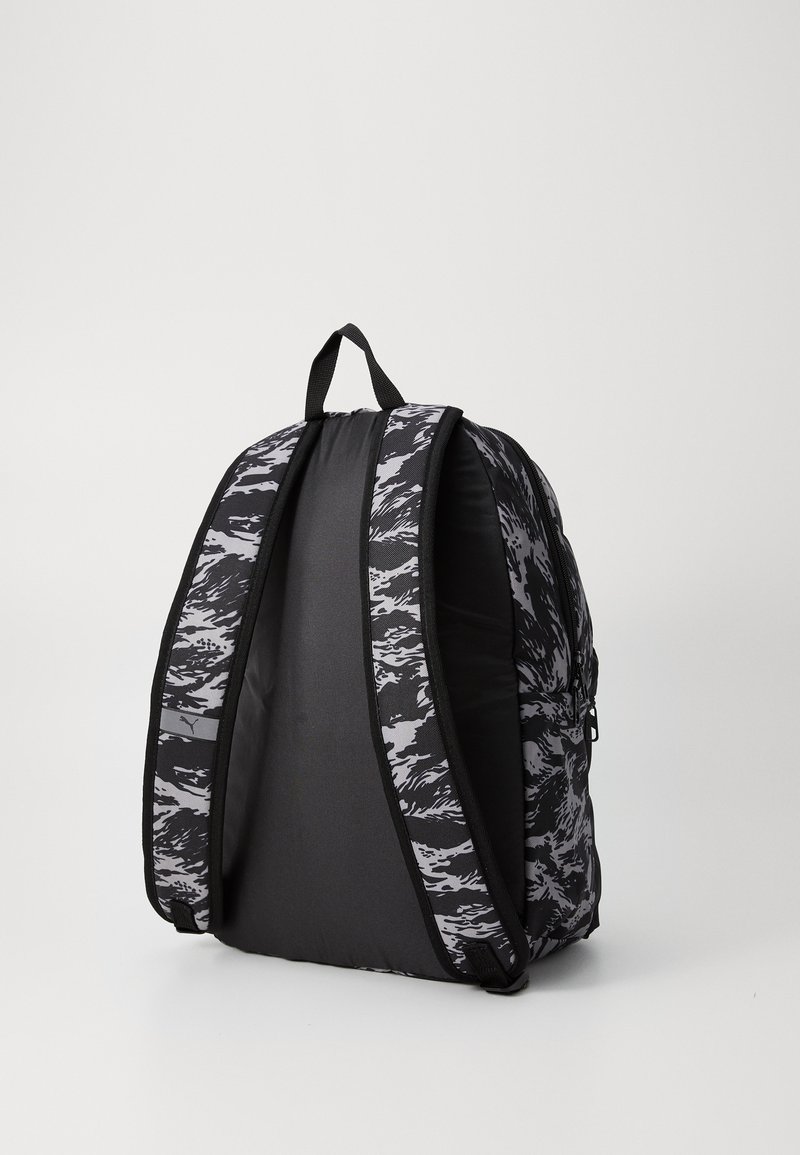 Sac à dos noir et gris avec un motif camouflage abstrait texturé. Conçu avec des bretelles rembourrées, une poignée supérieure et un compartiment zippé.