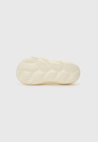 Szövetbélése könnyű, off-white gumi anyagból készült sneaker talp, mely sima és hullámszerű mintázattal rendelkezik a tapadás érdekében. Nincs látható márkajelzés.