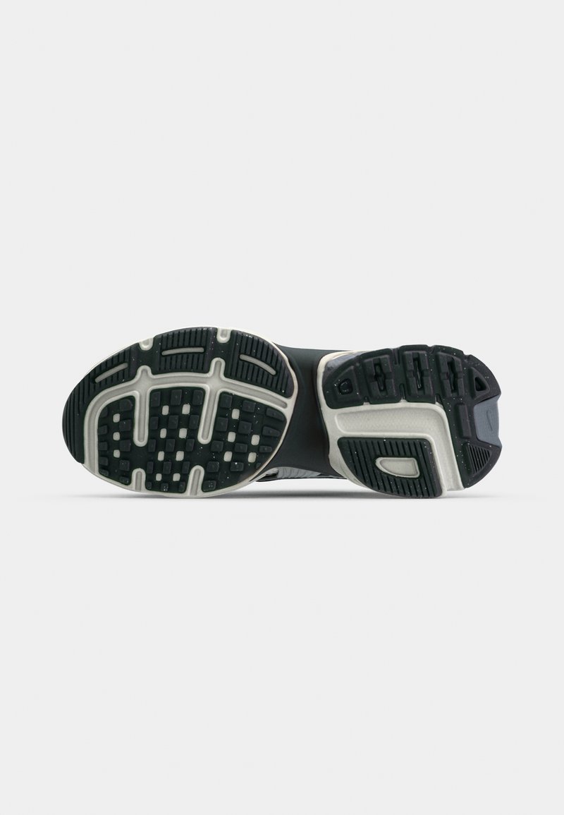Suela de zapato deportivo negra con goma texturizada para agarre, que presenta un diseño moldeado y acentos grises a lo largo de los bordes y la zona del talón.