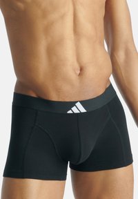 Svarta atletiska boxershorts med en strukturerad svart midjeband och en vit Adidas-logotyp, åtsittande design och slät bomullsmaterial.