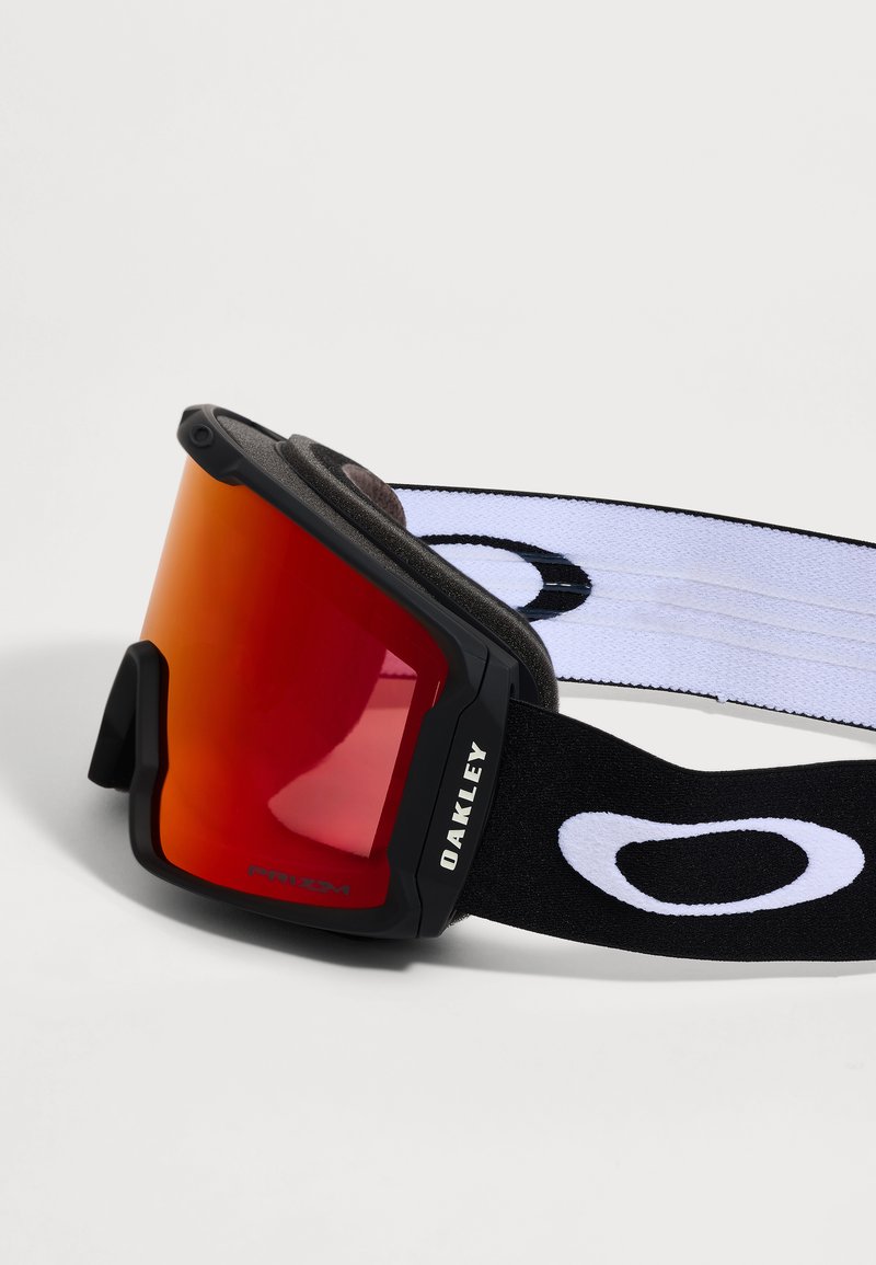 Ski goggles with red reflective lens, black frame, and black elastic strap featuring white Oakley logo on a white background.