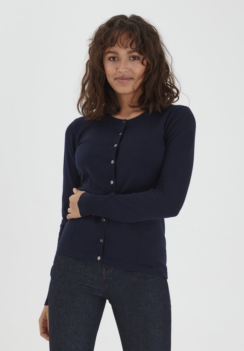 Cardigan blu navy con design aderente, maniche lunghe e chiusura con bottoni. Realizzato in materiale morbido e liscio, con semplici bottoni metallici.