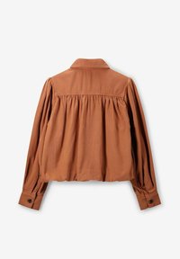 Blouse couleur rouille à manches longues, dos plissé, poignets boutonnés et col. Fabriquée en tissu doux avec une finition texturée.