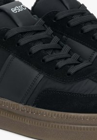 Czarne sneakersy z gładką skórzaną i zamszową cholewką, teksturowanymi sznurowadłami oraz gumową podeszwą z falistym wykończeniem na krawędzi.