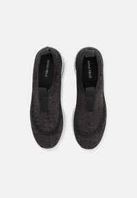 Svarta slip-on skor med en texturerad stickad överdel, elastiska remmar och en vit gummisula. Har en minimalistisk design som passar för avslappnad användning.