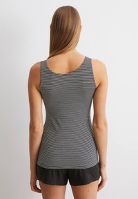 Schwarz-weißer gestreifter Tanktop mit runder Ausschnitt und ärmellosem Design, kombiniert mit schwarzen Shorts. Glatte Baumwollstruktur.