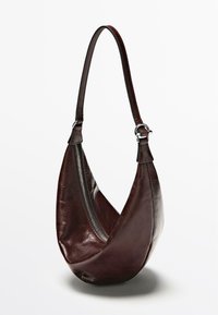 Bruine leren handtas met een gebogen ontwerp, enkele schouderriem en een zilveren ritssluiting langs de zijkant. Soepele textuur en strak gevormd.