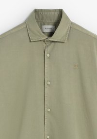 Camisa de color verde oliva con cuello, con botones en la parte delantera, de corte slim, hecha de tejido ligero, con un pequeño logo bordado en el lado izquierdo del pecho.