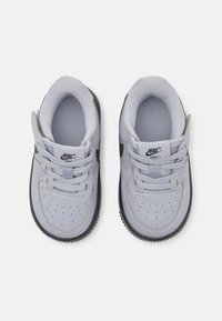 Szare syntetyczne sneakersy charakteryzują się wiązanym zapięciem, zaokrąglonym czubkiem, perforowanymi detalami oraz czarną gumową podeszwą. Logo Nike po boku.