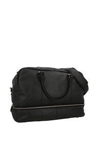 Černá kožená cestovní taška s dvojitými uchy a odnímatelným ramenním popruhem. Obsahuje stříbrný zip na spodní straně a hladký povrch.