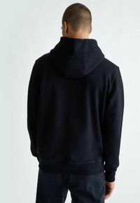 Felpa blu navy con cappuccio regolabile, vestibilità ampia, polsini e orlo ribattuti, e superficie esterna in morbido pile.