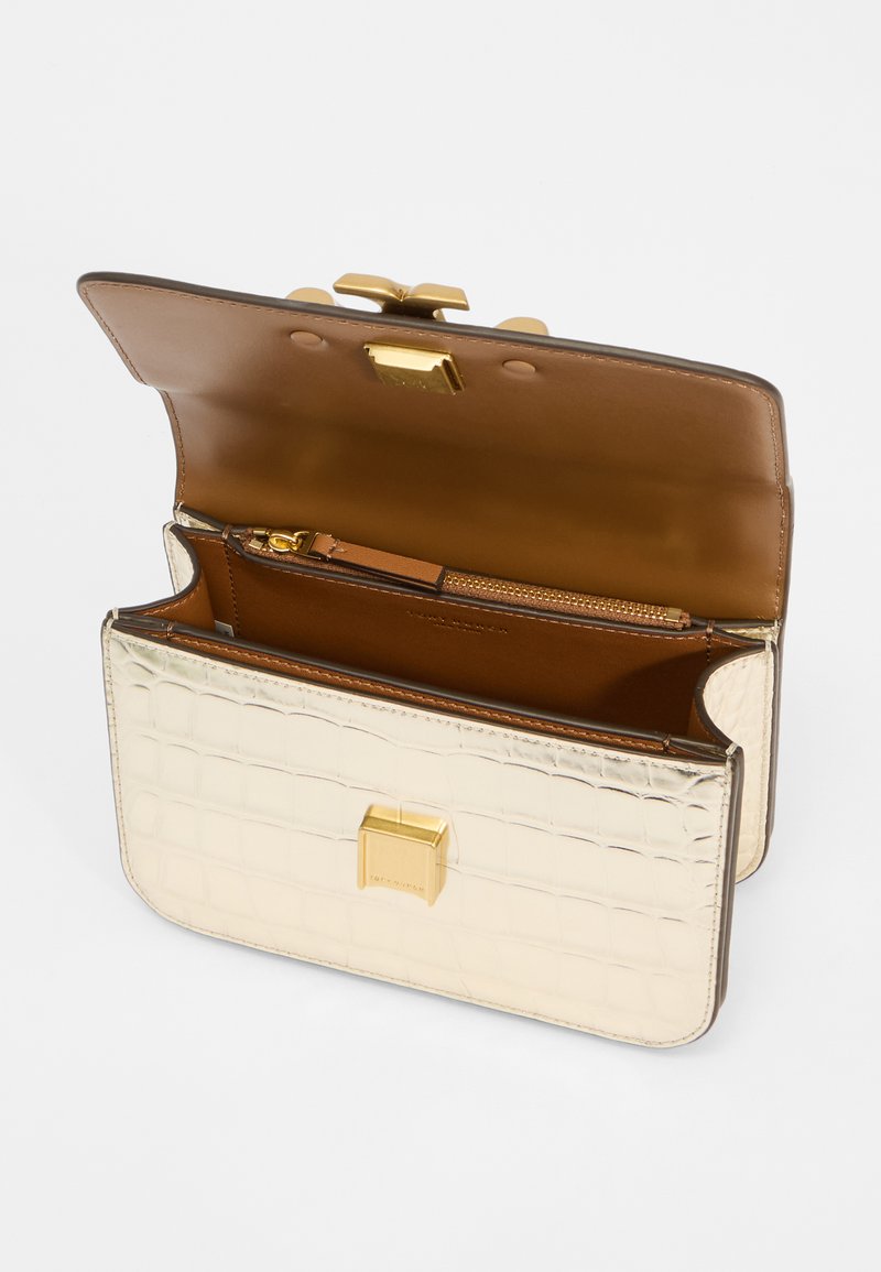 Metallisch goldene Handtasche mit Krokodilprägung, ausgestattet mit einem braunen Innenfutter, einem Reißverschlussfach und einem sicheren Verschluss.