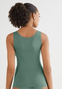 Zelený top bez rukávů vyrobený z měkké tkaniny, s kulatým výstřihem a přiléhavým střihem, s hladkou texturou a bez viditelných vzorů.