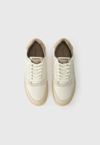 Une paire de baskets crème et beige AllSaints avec des lacets, une partie supérieure perforée au niveau des orteils et des semelles de couleur gomme, vue de dessus sur un fond blanc.