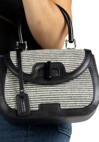 Schwarz-creamfarbige Handtasche mit einem strukturierten gewebten Muster, mit Lederdetails und einer strukturierten Form. Enthält einen abnehmbaren Tragegurt.