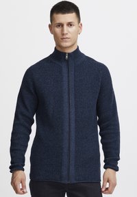 Suéter de punto azul marino con cremallera, de tejido texturizado, cuello alto y puños acanalados. Cuenta con una cremallera central y un patrón texturizado en todo su diseño.