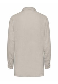 Camisa de manga larga en lino beige claro con un corte relajado, puños abotonados y un cuello clásico, que presenta una superficie texturizada.