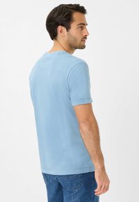 Lys blå, kortærmet t-shirt lavet af blødt stof. Rund halsudskæring, synlige syninger og en afslappet pasform. Bæres med blå jeans.