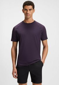 Purple short-sleeve athletic shirt with a crew neck, made from smooth fabric, featuring subtle branding on the chest and raglan sleeves.