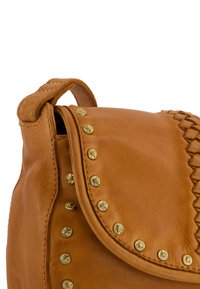 Sac en cuir marron avec une surface texturée, comportant des clous dorés sur le bord et un accent tressé sur le rabat. Design compact avec une poignée supérieure.