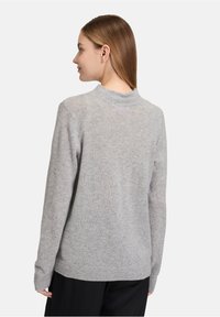 Gray knitted sweater with a high neckline, long sleeves, and ribbed cuffs. Soft texture; subtle variations in tone. Simple design.