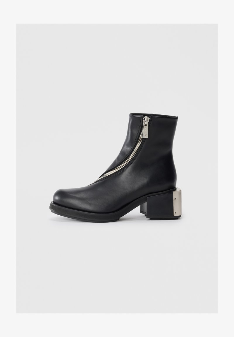Must musta ankle boot, mille külgse tõmbega, kaarjas varvas ja blokk-kand, milles on metalliline aktsent. Sile tekstuur ja kaasaegne siluett.