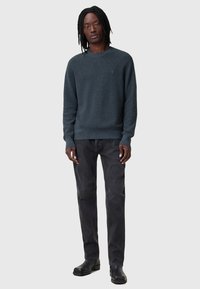Maglione grigio scuro a collo rotondo in maglia texturizzata, abbinato a jeans neri dritti sbiaditi e stivali neri per un look casual.