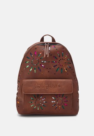 Sac à dos en cuir marron avec des découpes florales laissant apparaître un tissu coloré en dessous et une poche frontale embossée du nom de la marque.