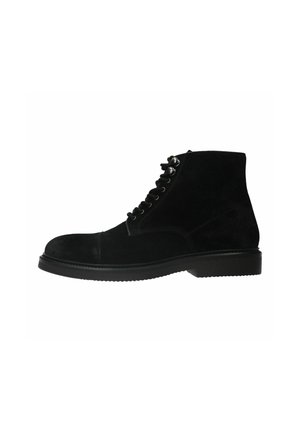 Bottines en suede noir avec un bout rond, un laçage sur le devant et une semelle plate en caoutchouc ; présentent des œillets en métal et une texture lisse.