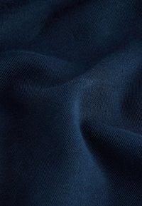 Mørkeblå stof, blød tekstur, med en glat, strikket udseende. Materialet har en let glans og et ensartet mønster hele vejen igennem.