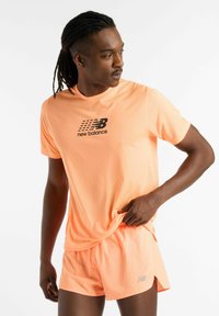 Bright orange athletic shirt with a textured surface and black logo, paired with matching shorts, showcasing a fitted design.