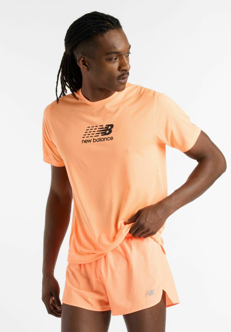 Bright orange athletic shirt with a textured surface and black logo, paired with matching shorts, showcasing a fitted design.