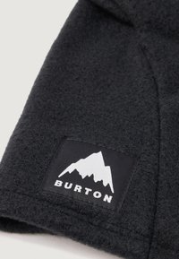 Fekete bolyhos anyag, amelyen egy négyzet alakú címke látható, fehér hegy grafikával és a "BURTON" felirattal fehér színben, az egyik sarkában hímezve.