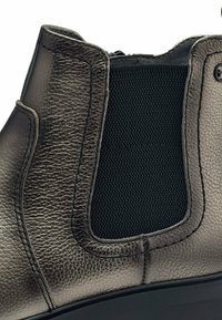 Metalizuotos pilkos kulkšniniai batai su tekstūruota oda, elastinė šoninė panelė ir tvirta juoda guma. Išsamus siuvinėjimas ties siūlėmis.