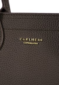 Hallhalli halliskatte, millel on hall tekstuuriga nahk ja kullaga "CArlheim" logo. Kujunduses on kasutatud tugevdustikat ja stiilset, struktureeritud kuju.