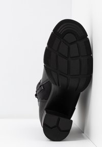 Chaussures noires avec une semelle en caoutchouc texturée, dotées d'une tige en cuir lisse et d'accents en nylon. Design profilé avec un talon solide.