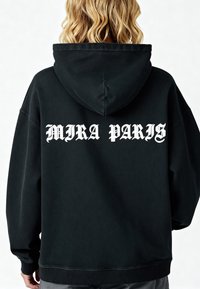 Felpa nera con una vestibilità rilassata, cappuccio, polsini a coste e testo "MIRA PARIS" in grassetto con carattere gotico bianco sulla schiena. Tessuto testurizzato.